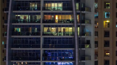 Geceleri apartmanda insanların oturduğu parlak pencereler..