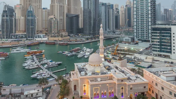 Yachter i Dubai Marina flankeras av Al Rahim moskén och bostadstorn och skyskrapor antenn dag till natt timelapse. — Stockfoto