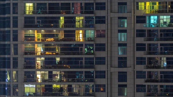 Des rangées de fenêtres rougeoyantes avec des personnes dans l'immeuble la nuit . — Photo