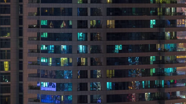 Des rangées de fenêtres rougeoyantes avec des personnes dans l'immeuble la nuit . — Photo