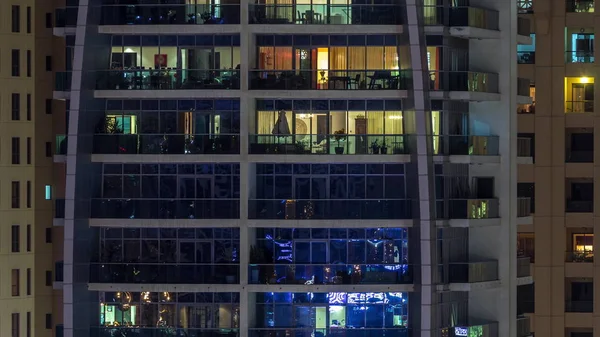 Γραμμές από λαμπερά παράθυρα με τους ανθρώπους στην πολυκατοικία τη νύχτα. — Φωτογραφία Αρχείου