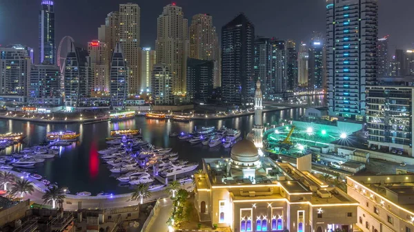 Yachter i Dubai Marina flankeras av Al Rahim moskén och bostadstorn och skyskrapor antenn natt timelapse. — Stockfoto