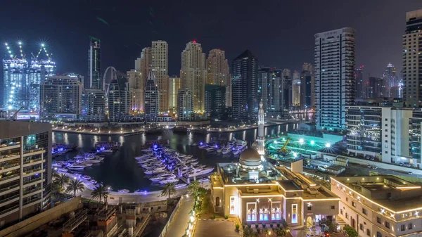 Yachter i Dubai Marina flankeras av Al Rahim moskén och bostadstorn och skyskrapor antenn natt timelapse. — Stockfoto