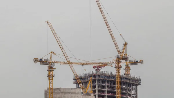 Aerial view of a skyscraper under construction with huge cranes timelapse in Dubai marina. — ストック写真