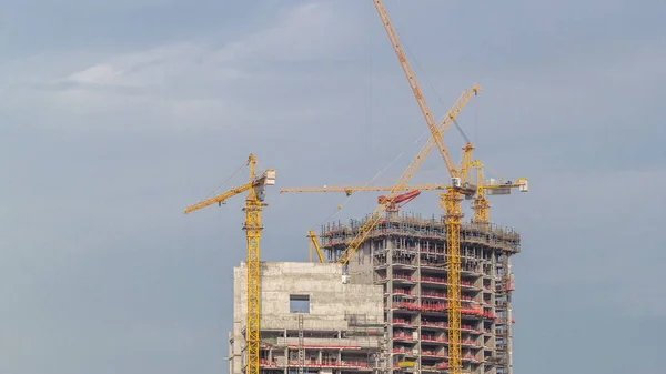 Widok z powietrza na wieżowiec w budowie z ogromnymi żurawiami timelapse w porcie w Dubaju. — Zdjęcie stockowe