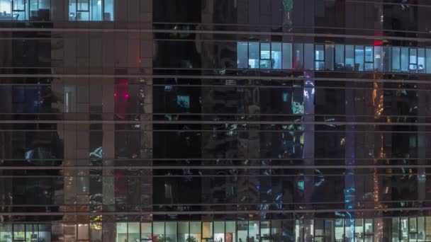 Εξωτερικό ουρανοξύστη στο γραφείο, αργά το βράδυ, με εσωτερικά φώτα και άτομα που εργάζονται μέσα στη νύχτα. — Αρχείο Βίντεο