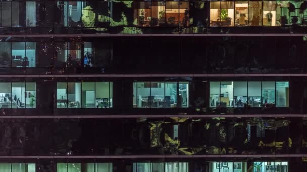 Oficina rascacielos exterior durante la tarde con luces interiores encendidas y personas que trabajan dentro de la noche timelapse — Vídeo de stock