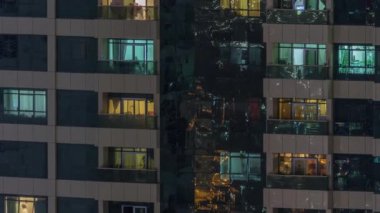 Dış apartman zaman atlamalı gece görünümü. Pencerelerde yanıp sönen ışıklar ile yüksek katlı gökdelen
