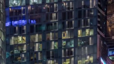 Dış apartman kulesinin gece görüşü. Pencerelerinde yanıp sönen ışıklar olan yüksek gökdelen