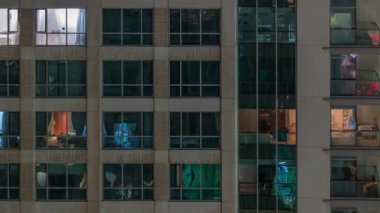 Çok katlı binanın içinde aydınlatma ve apartmanlarda zaman atlamalı insanları hareket ettiren pencereler.