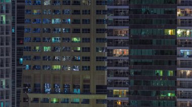 Geceleri apartmanda insanların oturduğu parlak pencereler..