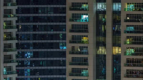 Des rangées de fenêtres rougeoyantes avec des personnes dans l'immeuble la nuit . — Photo