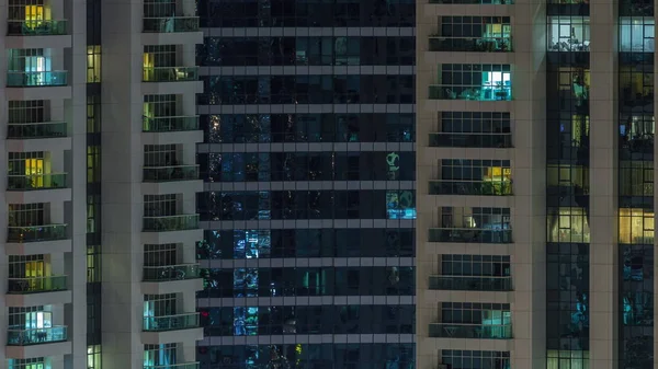 Des rangées de fenêtres rougeoyantes avec des personnes dans l'immeuble la nuit . — Photo