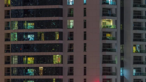 Рядки сяючих вікон з людьми в житловому будинку вночі . — стокове фото