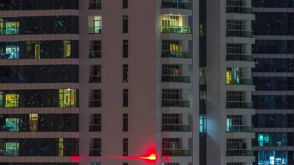 밤에 아파트 건물에 있는 사람들 과 함께 빛나는 창문들이 줄지어서 있다. — 스톡 사진