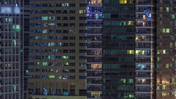 Des rangées de fenêtres rougeoyantes avec des personnes dans l'immeuble la nuit . — Photo