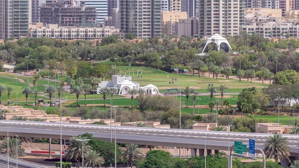 Pole golfowe w Dubaju z pejzażem miejskim dzielnic Gereens i tecom w tle antenowy timelapse — Zdjęcie stockowe