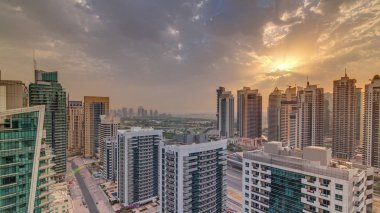 Dubai Marina 'daki çeşitli gökdelenlerin ve kulelerin gündoğumu manzarası yukarıdaki hava zaman aralığından