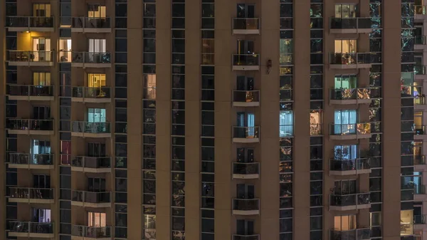 一排排明亮的窗户，晚上有很多人在公寓楼里. — 图库照片