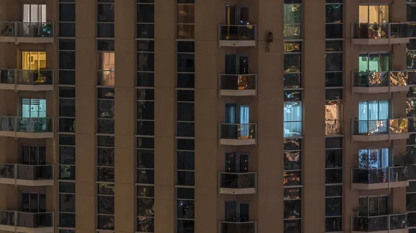 Des rangées de fenêtres rougeoyantes avec des personnes dans l'immeuble la nuit . — Photo