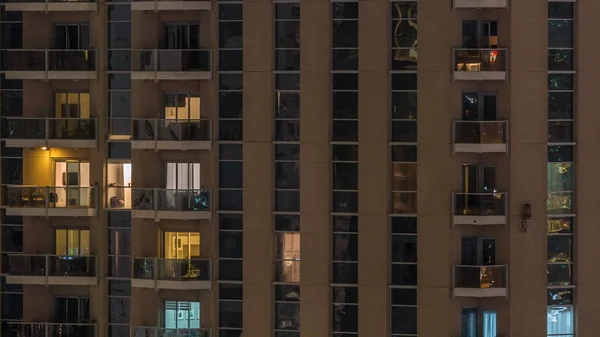 Рядки сяючих вікон з людьми в житловому будинку вночі . — стокове фото