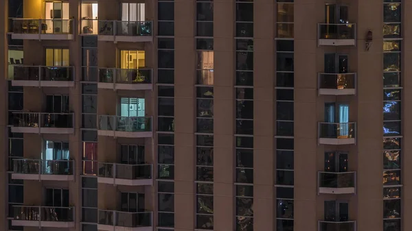 Righe di finestre luminose con persone in condominio di notte . — Foto Stock