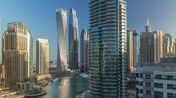 Aerial view of Dubai Marina residential and office skyscrapers with waterfront timelapse. Morning after sunrise with shadows moving fast. Sun reflected from glass. Floating boats and yachts