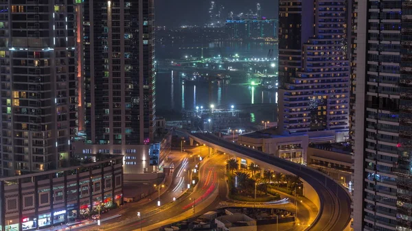 Vista aérea a los rascacielos del puerto deportivo de Dubái con sitio de construcción e isla Palm Jumeirah en el timelapse nocturno de fondo . —  Fotos de Stock