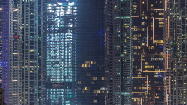 View of various skyscrapers and towers in Dubai Marina from above aerial night timelapse. Illuminated modern buildings in urban skyline with construction site