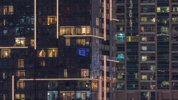 Des rangées de fenêtres rougeoyantes avec des personnes dans l'immeuble la nuit . — Photo