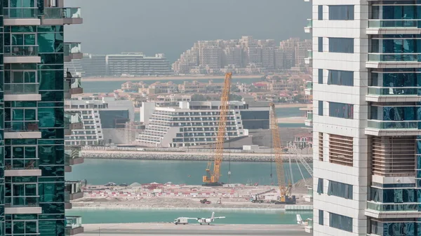 Luchtfoto naar Dubai jachthaven wolkenkrabbers met bouwplaats en Palm Jumeirah Island op achtergrond timelapse. — Stockfoto