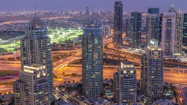 Dubai Marina arranha-céus e torres do lago jumeirah vista do topo do dia aéreo para a noite timelapse nos Emirados Árabes Unidos . — Fotografia de Stock
