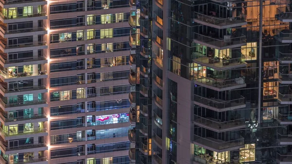 Des rangées de fenêtres rougeoyantes avec des personnes dans l'immeuble la nuit . — Photo