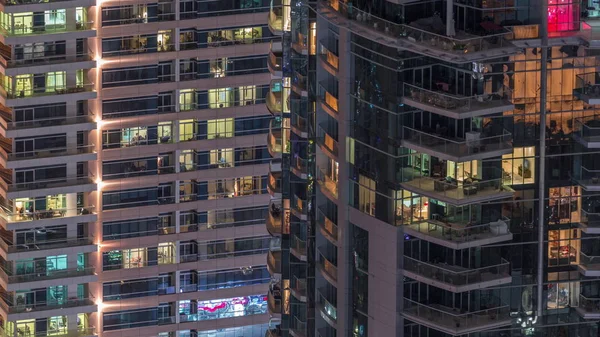 Fileiras de janelas brilhantes com pessoas no prédio de apartamentos à noite . — Fotografia de Stock