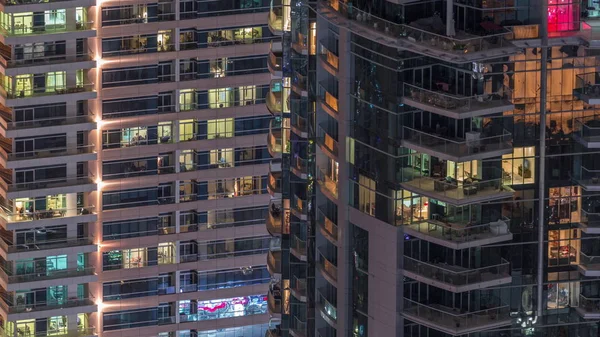 Des rangées de fenêtres rougeoyantes avec des personnes dans l'immeuble la nuit . — Photo