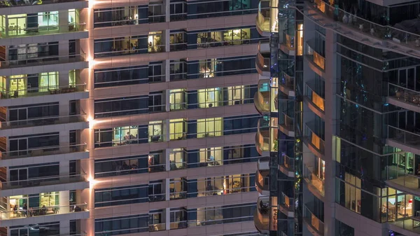 Des rangées de fenêtres rougeoyantes avec des personnes dans l'immeuble la nuit . — Photo