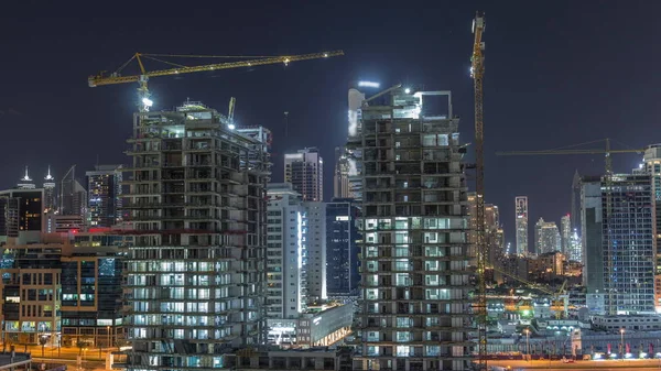 Luchtfoto van een wolkenkrabber in aanbouw met enorme kranen nachtelijke tijdspanne in Dubai. — Stockfoto