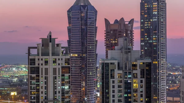 Blick auf beleuchtete Wolkenkratzer mit Lichtern aus Fenstern in Dubai im Zeitraffer bei Sonnenuntergang — Stockfoto