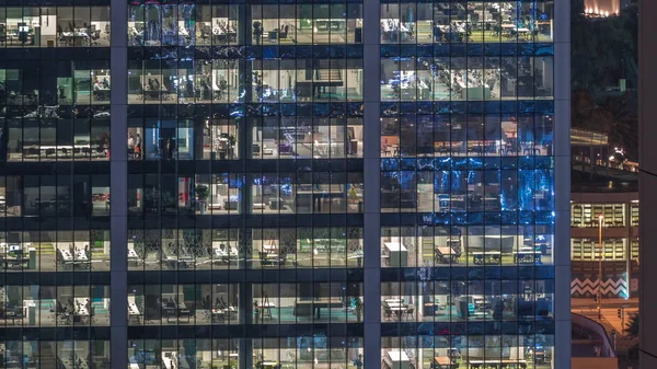 Kantoorgebouw exterieur tijdens de late avond met interieur verlichting en mensen die binnen de nacht timelapse werken — Stockfoto