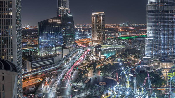 Panoramic skyline view of Dubai downtown with mall, fountains and Burj Khalifa aerial night timelapse with traffic. Modern illuminated skyscrapers and construction site
