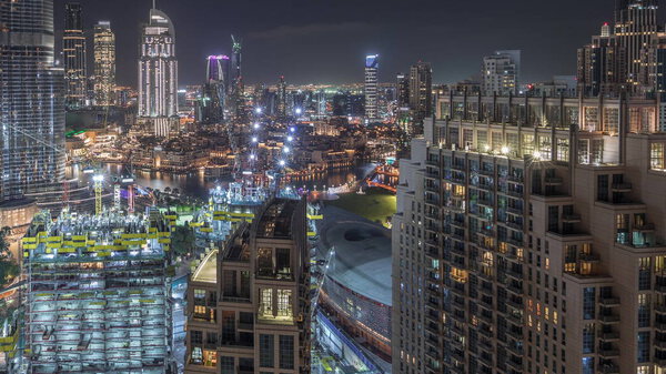 Dubai downtown skyscrapers amazing aerial view at night timelapse with fountains, Dubai, United Arab Emirates. Illuminated modern towers and construction site with cranes
