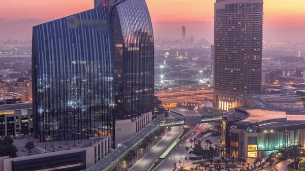 Dubai downtown street with busy traffic and skyscrapers around night to day transition timelapse. Modern road and urban buildings with mall aerial view. Sheikh Mohammed bin Rashid Blvd