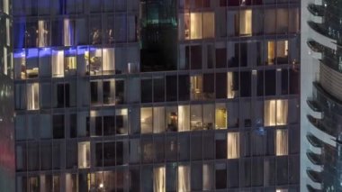 Dış apartman kulesinin gece görüşü. Pencerelerinde yanıp sönen ışıklar olan yüksek gökdelen