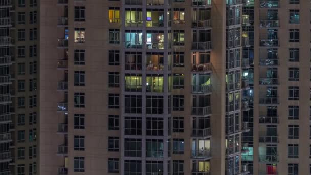 Fenster des mehrstöckigen Gebäudes mit Beleuchtung im Inneren und beweglichen Menschen in Wohnungen Zeitraffer. — Stockvideo