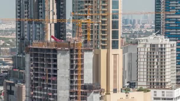 Luchtfoto van een wolkenkrabber in aanbouw met enorme kranen in Dubai timelapse. Verenigde Arabische Emiraten — Stockvideo