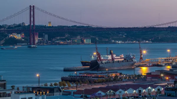 Skyline πάνω από το εμπορικό λιμάνι της Λισαβόνας μέρα με τη νύχτα timelapse, 25 Απριλίου Γέφυρα, εμπορευματοκιβώτια στην προβλήτα με γερανούς εμπορευμάτων — Φωτογραφία Αρχείου