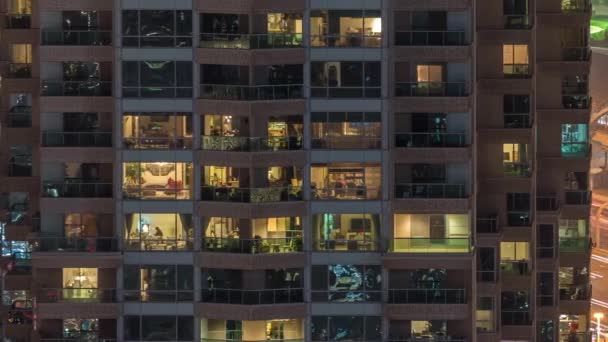 Lights in windows of modern multiple story building in urban setting at night timelapse — Stock Video