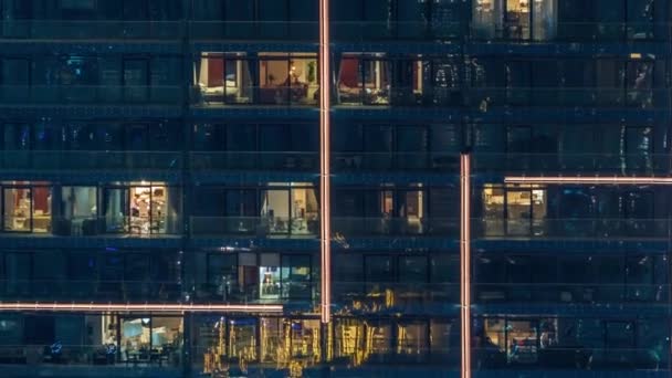 야간 경과에 도시 설정에서 현대 여러 층 건물의 창에 조명 — 비디오