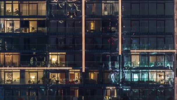 Lys i vinduer i moderne fleretasjes bygning i urbane omgivelser om natten – stockvideo