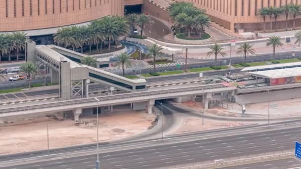 Bovenaanzicht van het verkeer in de buurt van het winkelcentrum met voetgangersbrug van tramhalte timelapse in Dubai Marina in Dubai, VAE. — Stockvideo